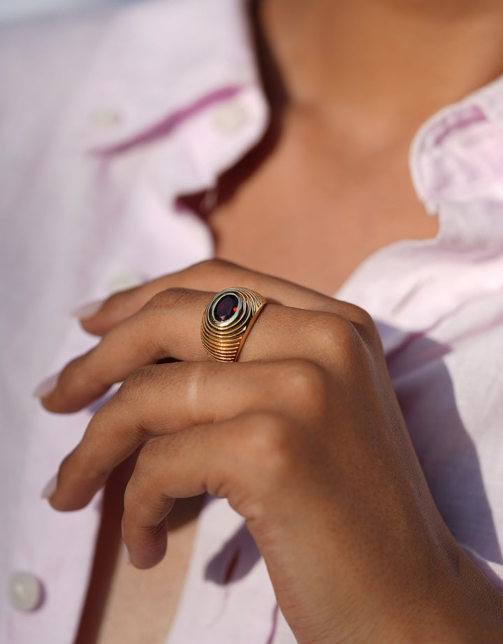 Bague Buren Chubby grenat en laiton doré, inspirée des colonnes du Palais Royal parisien, portée à la main
