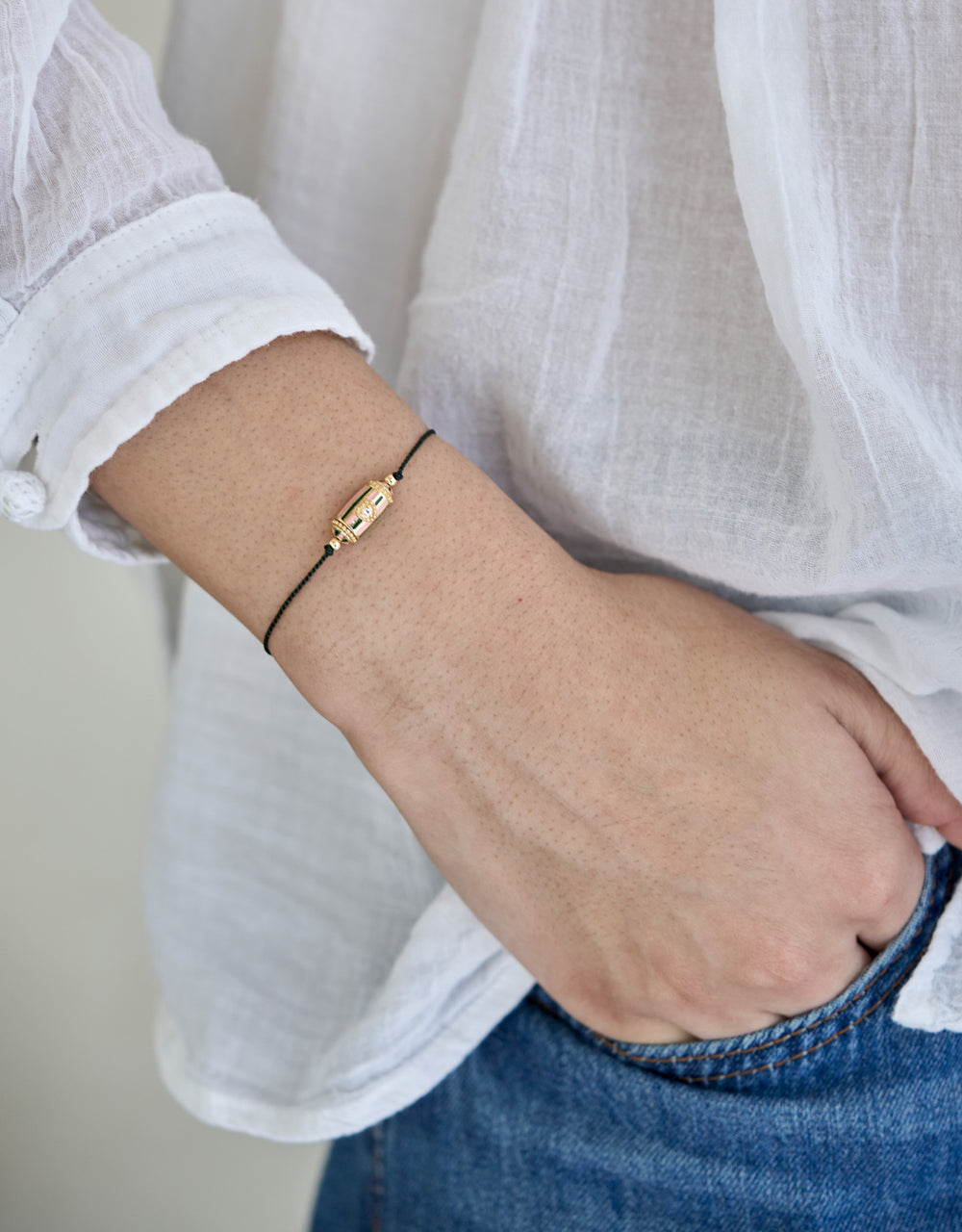 Bracelet Rakhi Lola laiton plaqué or, fil rouge symbole de protection, porté au poignet avec intention