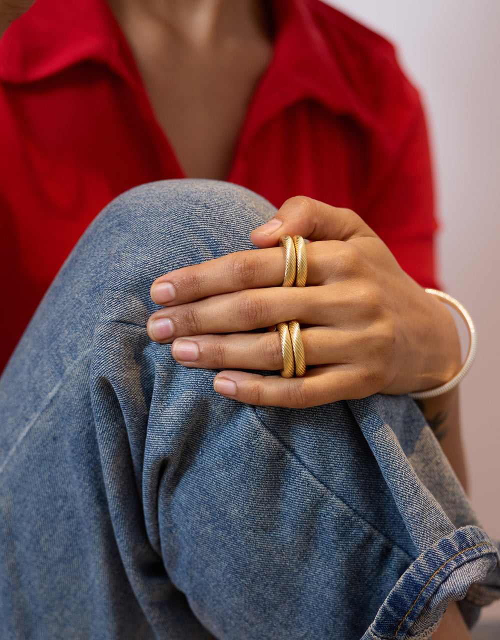 Bague Twisted dorée en laiton plaqué or 24 carats, portée sur la main avec bracelets assortis, style créateur élégant